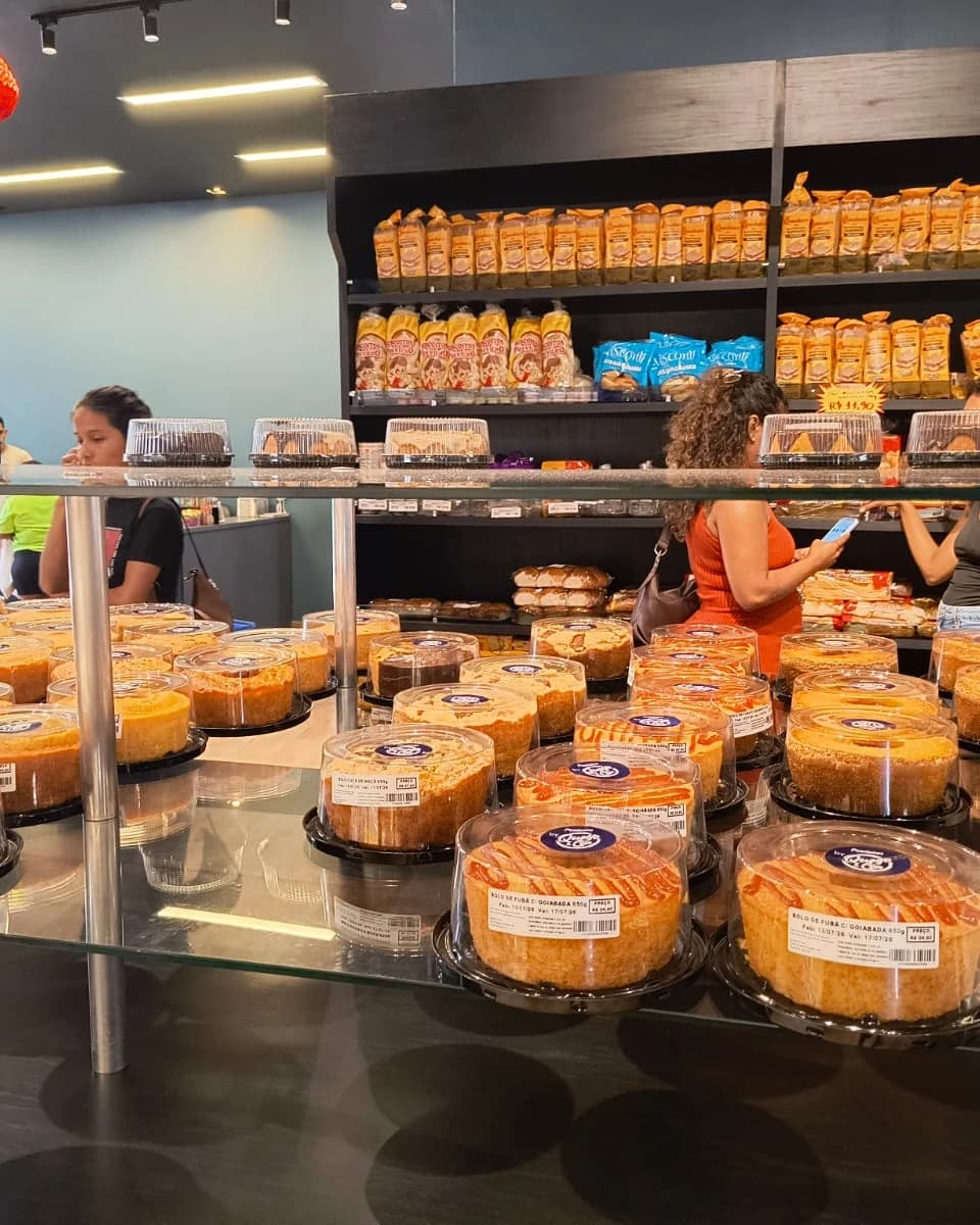 Vitrine de bolos da Queijo & Cia, clientes escolhendo no balcão